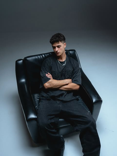 Portrait of VANISH seated in a black armchair